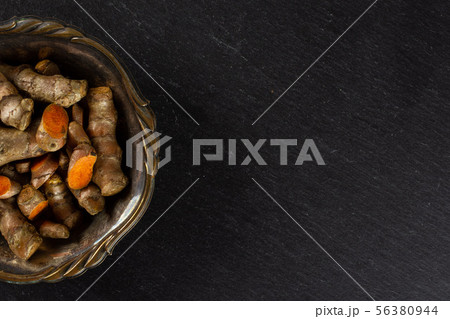 Bright turmeric rhizome on grey stone 56380944
