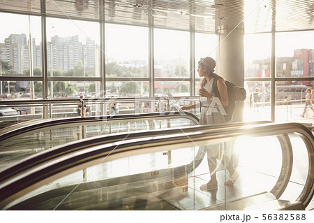 Portrait Smiling Woman Wearing Hat In Airport At Escalator. people traveling with hand luggage Portrait Smiling Woman Wearing Hat In Airport At Escalator. people traveling with hand luggage 56382588