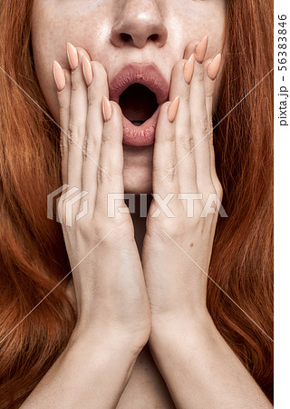 Wow Portrait of young and shocked redhead woman keeping mouth opened while standing against grey Wow Portrait of young and shocked redhead woman keeping mouth opened while standing against grey 56383846