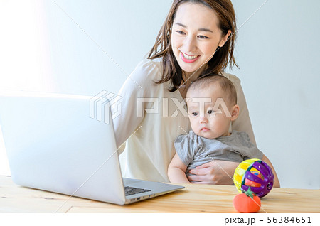 子供を抱きながらパソコンを操作する女性 子供を抱きながらパソコンを操作する女性 56384651