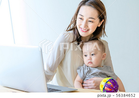 子供を抱きながらパソコンを操作する女性 子供を抱きながらパソコンを操作する女性 56384652