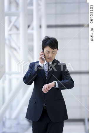 通話しながら腕時計を見るビジネスマン 通話しながら腕時計を見るビジネスマン 56453105