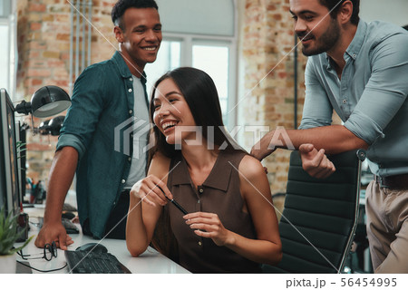 Perfect teamwork. Group of young and cheerful three people discussing new ideas and smiling while Perfect teamwork. Group of young and cheerful three people discussing new ideas and smiling while 56454995