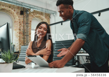 Good news Young afro american man in casual clothes showing data on his digital tablet and Good news Young afro american man in casual clothes showing data on his digital tablet and 56456336