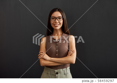 Smart and confident. Young asian businesswoman in casual wear and eyeglasses keeping arms crossed 56459297