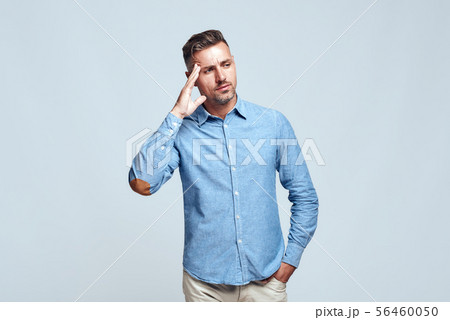 Lost in thoughts. Portrait of young and smart bearded man in casual wear touching his head and Lost in thoughts. Portrait of young and smart bearded man in casual wear touching his head and 56460050