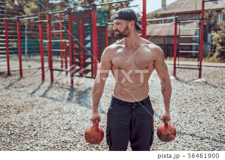 Athletic man working out with a kettlebell at street gym yard. Strength and motivation. 56461900