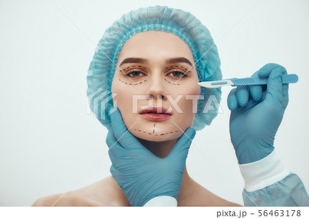 Face lift surgery. Portrait of beautiful young woman in blue medical hat having cosmetic face 56463178