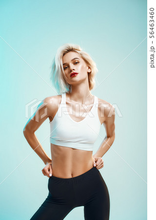 I am sexy. Beautiful young woman in white top adjusting her black leggings and looking at camera 56463460