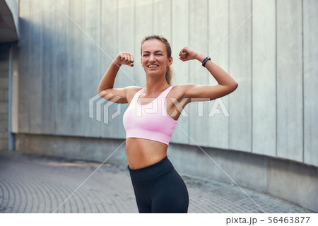 Strength and motivation. Happy young woman in sports clothing showing her strong hands and smiling 56463877