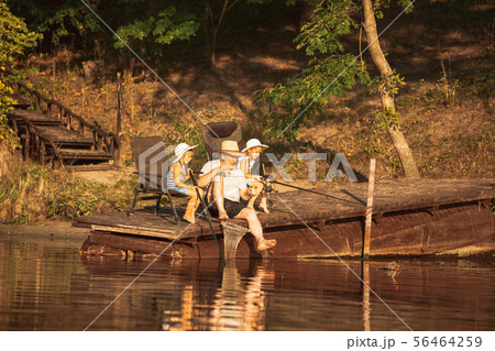 Cute little girls and their granddad are on fishing at the lake or river Cute little girls and their granddad are on fishing at the lake or river 56464259
