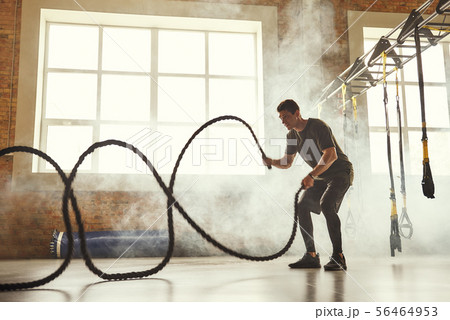 CrossFit training. Side view of young athletic man with perfect body doing crossfit exercises with a CrossFit training. Side view of young athletic man with perfect body doing crossfit exercises with a 56464953