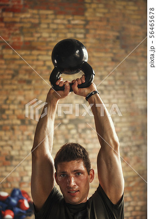 Strong and handsome man holding big black dumbbell under his head while exercising at gym. Weight Strong and handsome man holding big black dumbbell under his head while exercising at gym. Weight 56465678