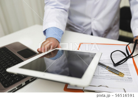Doctor working with tablet computer at desk. 56516591
