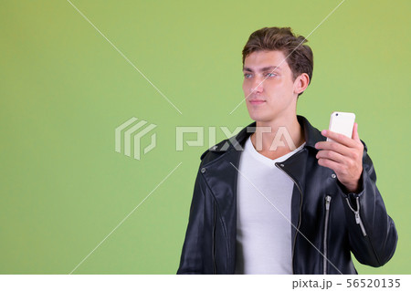 Portrait of young rebellious man thinking while using phone 56520135