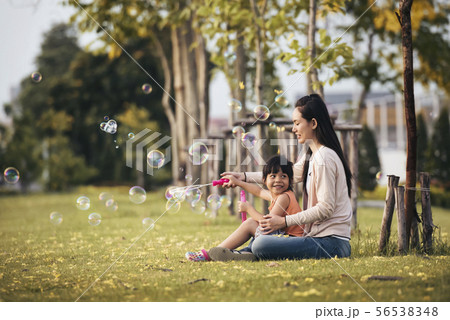 Happy Asian mother and daughter blowing bubbles in Happy Asian mother and daughter blowing bubbles in 56538348