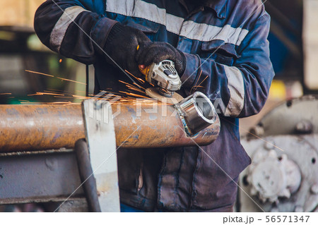 Workers in a foundry grind castings with a grinding machine - Heavy industry workplace. 56571347