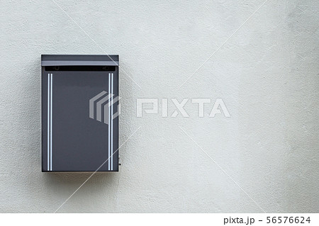Gray metal mailbox mounted on the cement wall 56576624