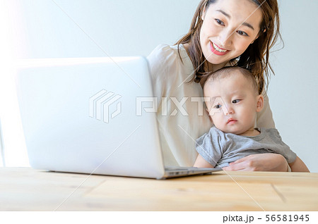 子供を抱きながらパソコンを操作する女性 子供を抱きながらパソコンを操作する女性 56581945
