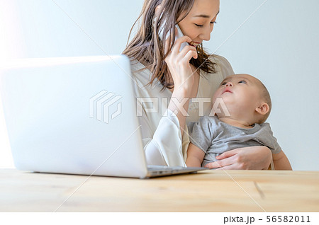 子供を抱きながら電話をする女性 子供を抱きながら電話をする女性 56582011