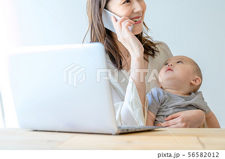 子供を抱きながら電話をする女性 子供を抱きながら電話をする女性 56582012