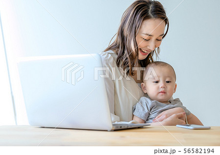 子供を抱きながら仕事をする女性 子供を抱きながら仕事をする女性 56582194