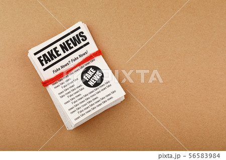 Stack of FAKE NEWS newspapers over brown paper 56583984