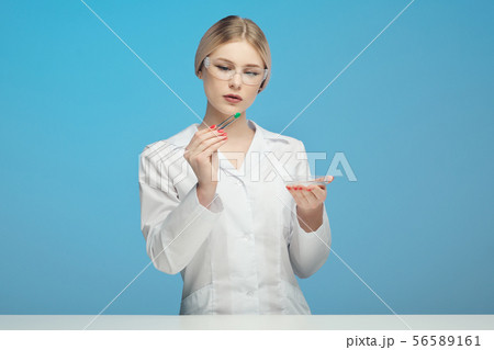 A scientist biologist pharmaceft woman in the laboratory examines the green material in a white coat 56589161