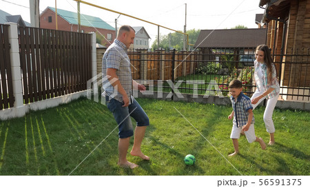 parents enjoy life playing football with active boy on lawn parents enjoy life playing football with active boy on lawn 56591375