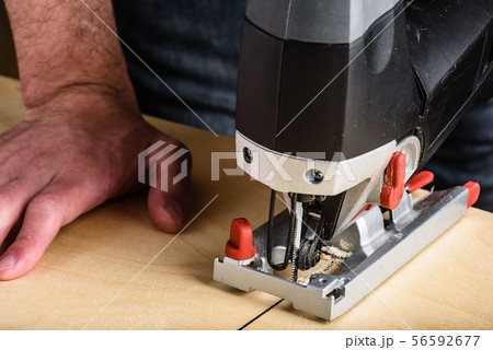 Man with electric jig saw cutting wood 56592677