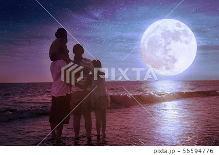 family standing on beach and watching the 56594776