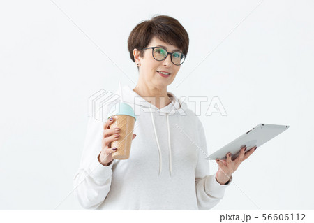 Beautiful woman 50 years old with short hair holding tablet and drinking cocktail from funny shaker 56606112