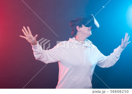 Smile happy woman getting experience using VR headset glasses of virtual reality on red-blue Smile happy woman getting experience using VR headset glasses of virtual reality on red-blue 56606250