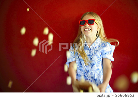 Little girl wearing sunglasses and eating popcorn Little girl wearing sunglasses and eating popcorn 56606952