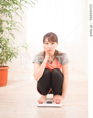 体重を量って落ち込む女性 体重を量って落ち込む女性 56609435