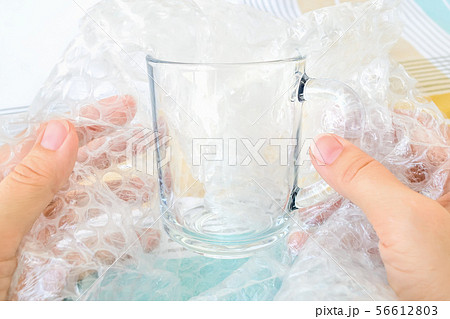 Woman hands package glass tea cup with bubble wrap 56612803
