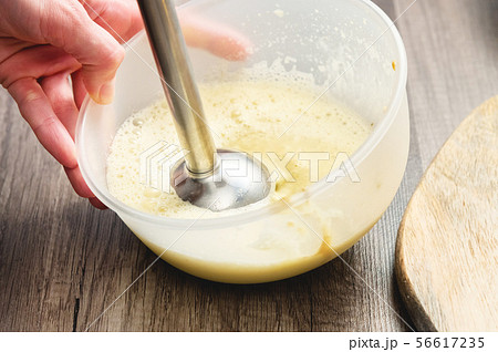 close-up whipping the mixture of homemade mayonnaise with a blender in a plastic bowl close-up whipping the mixture of homemade mayonnaise with a blender in a plastic bowl 56617235