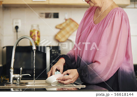 Woman rinsing plate under tap water Woman rinsing plate under tap water 56618144