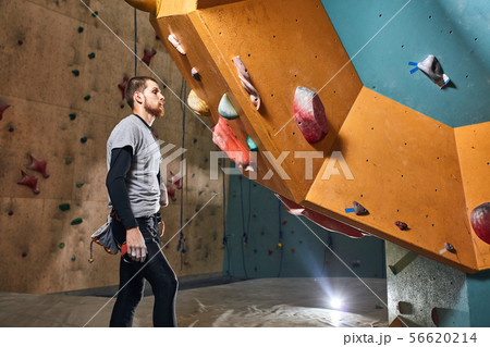 Athletic sportsman without forearm standing in front of artificial rock wall Athletic sportsman without forearm standing in front of artificial rock wall 56620214