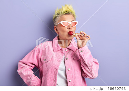 funny woman with dyed yellow hairstyle enjoying eating sweets funny woman with dyed yellow hairstyle enjoying eating sweets 56620748
