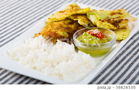 Leaves of cabbage in batter with rice and green sauce on a plate Leaves of cabbage in batter with rice and green sauce on a plate 56626530