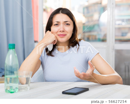 Upset girl suffering from troubles at table with bottled water 56627254