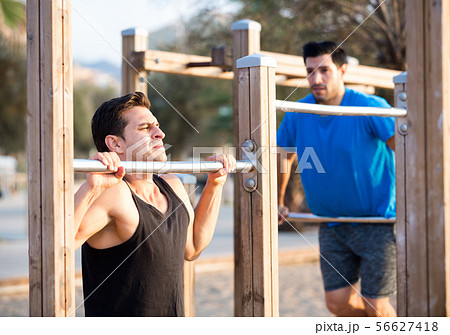 Smiling adult men are doing pull-ups Smiling adult men are doing pull-ups 56627418