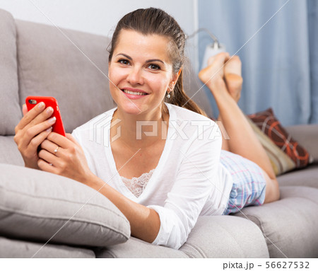 Woman lying on sofa with phone 56627532
