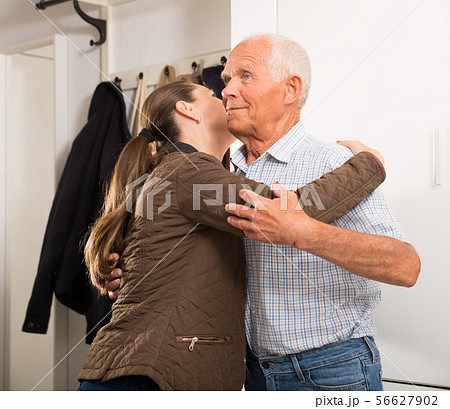 Woman in jacket and father hugging at the entrance to apartment Woman in jacket and father hugging at the entrance to apartment 56627902