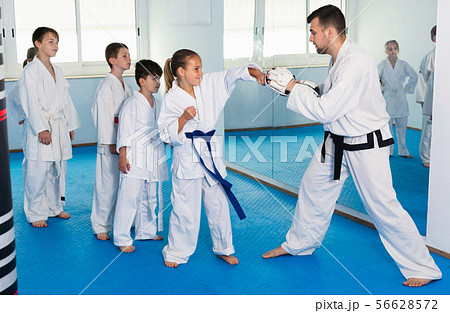 Children training karate kicks on punching bag during karate class Children training karate kicks on punching bag during karate class 56628572