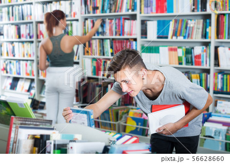 Teenager boy searching for new book on shelves Teenager boy searching for new book on shelves 56628660