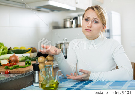 Portrait of tired woman at kitchen table Portrait of tired woman at kitchen table 56629401