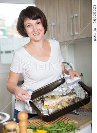 Woman with dorado fish in baking tray 56629625