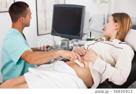 Man sonographer examining female patient 56630913